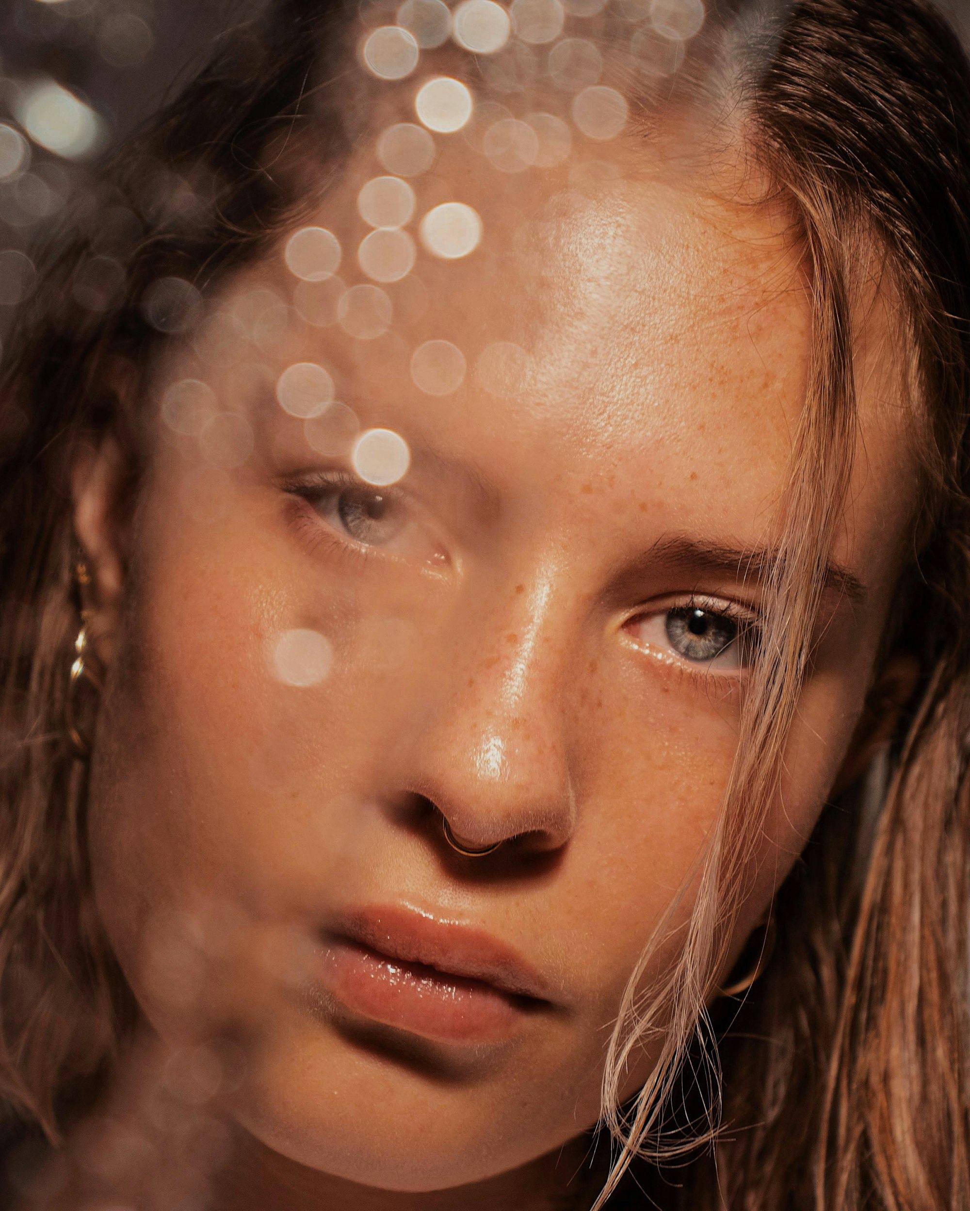 Close-up portrait of a woman with glowing, freckled skin
